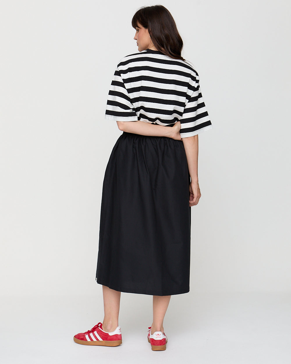 Person wearing a black and white striped shirt and black skirt on a white background