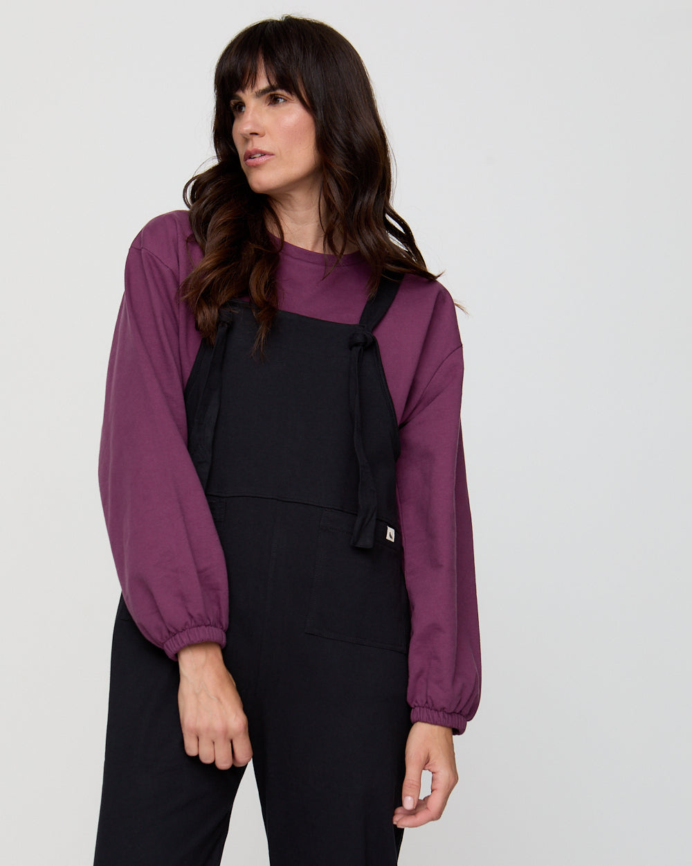 Woman wearing a purple jacket over a black outfit on a white background