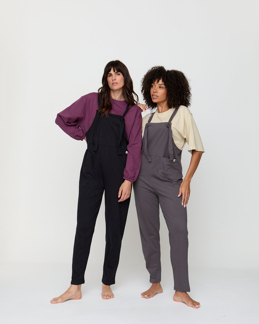 Two people wearing black and gray overalls against a white background