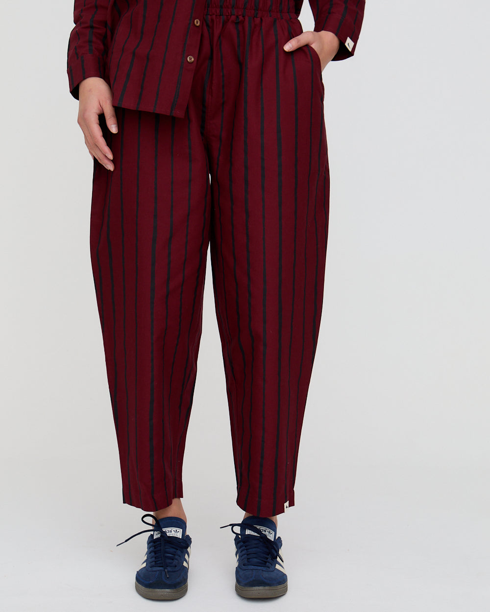 Person wearing maroon striped pants with a white background