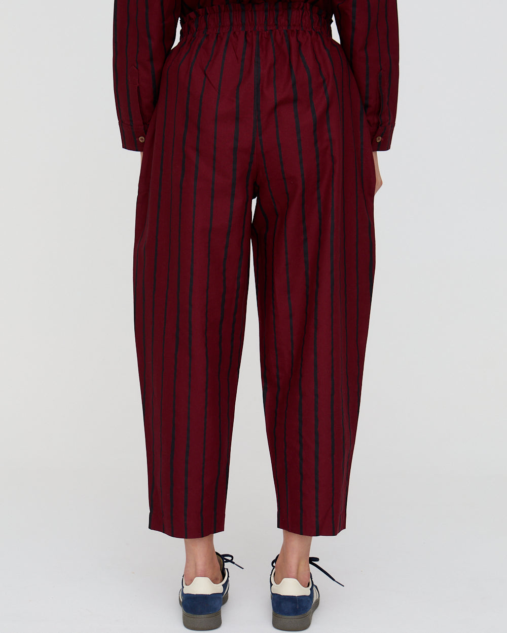 Maroon striped pants worn by a person on a white background
