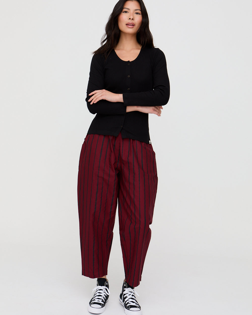 Woman wearing a black top and red striped pants on a white background