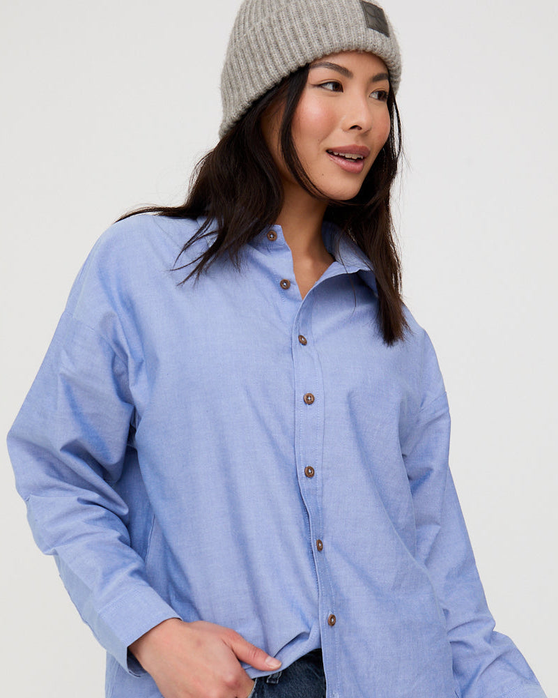 Woman wearing a light blue shirt and dark jeans on a white background