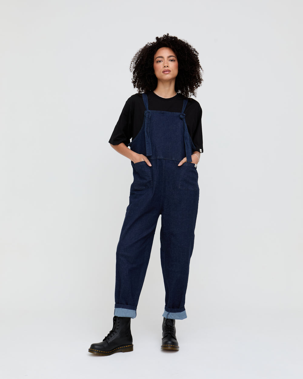 Person wearing navy blue denim overalls on a white background