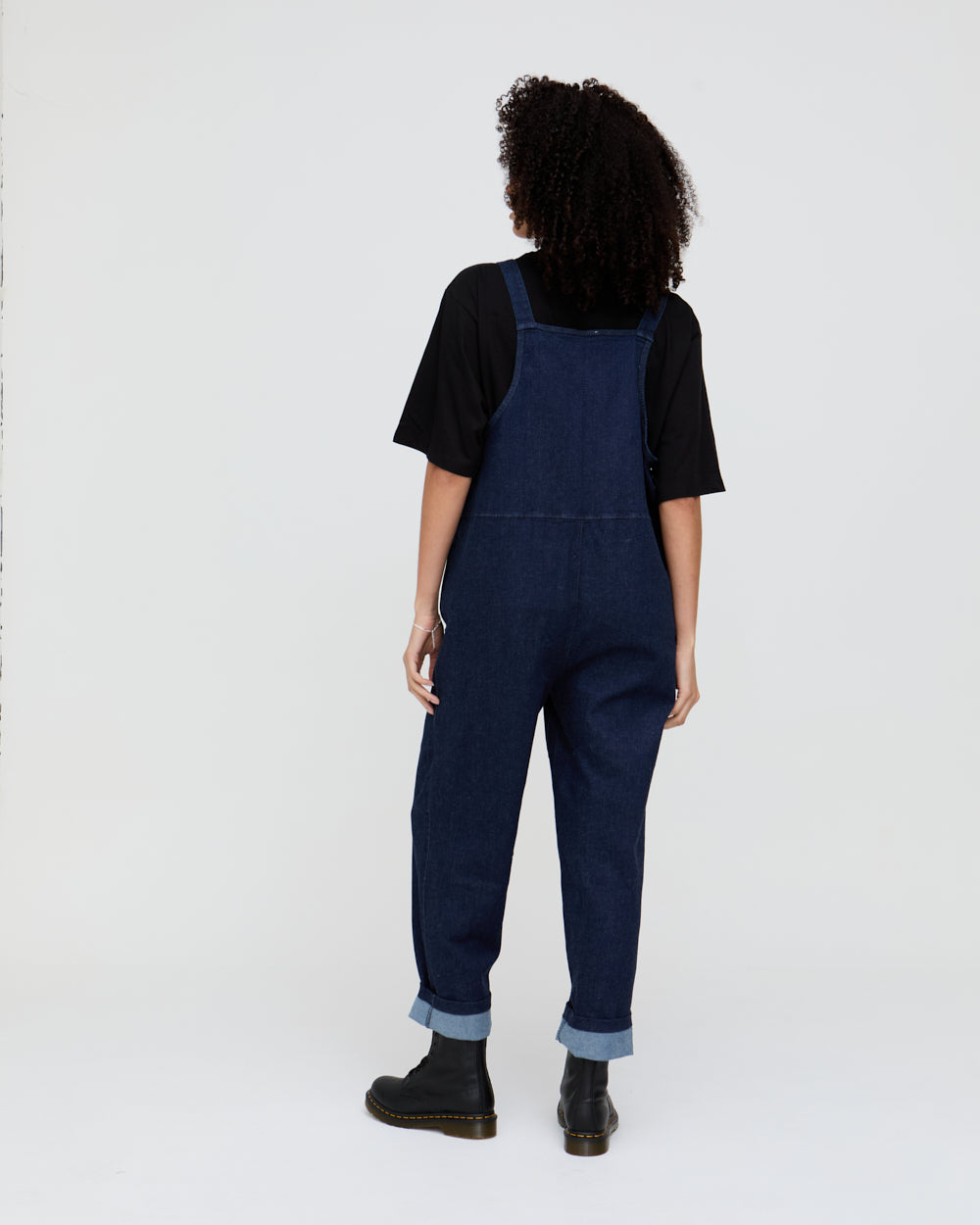 Person wearing blue denim overalls on a white background