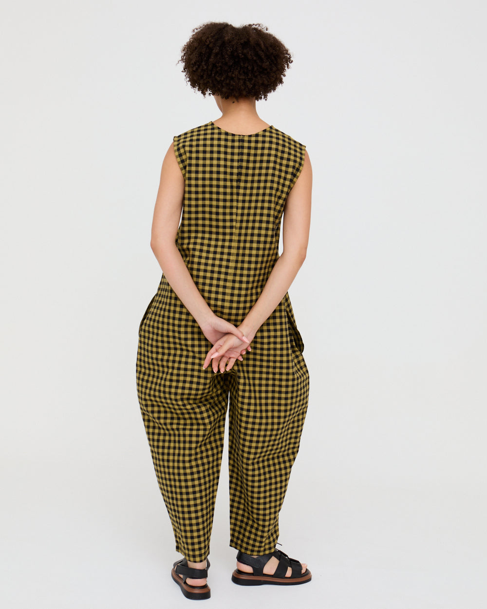 Person wearing a yellow and black checkered jumpsuit on a white background