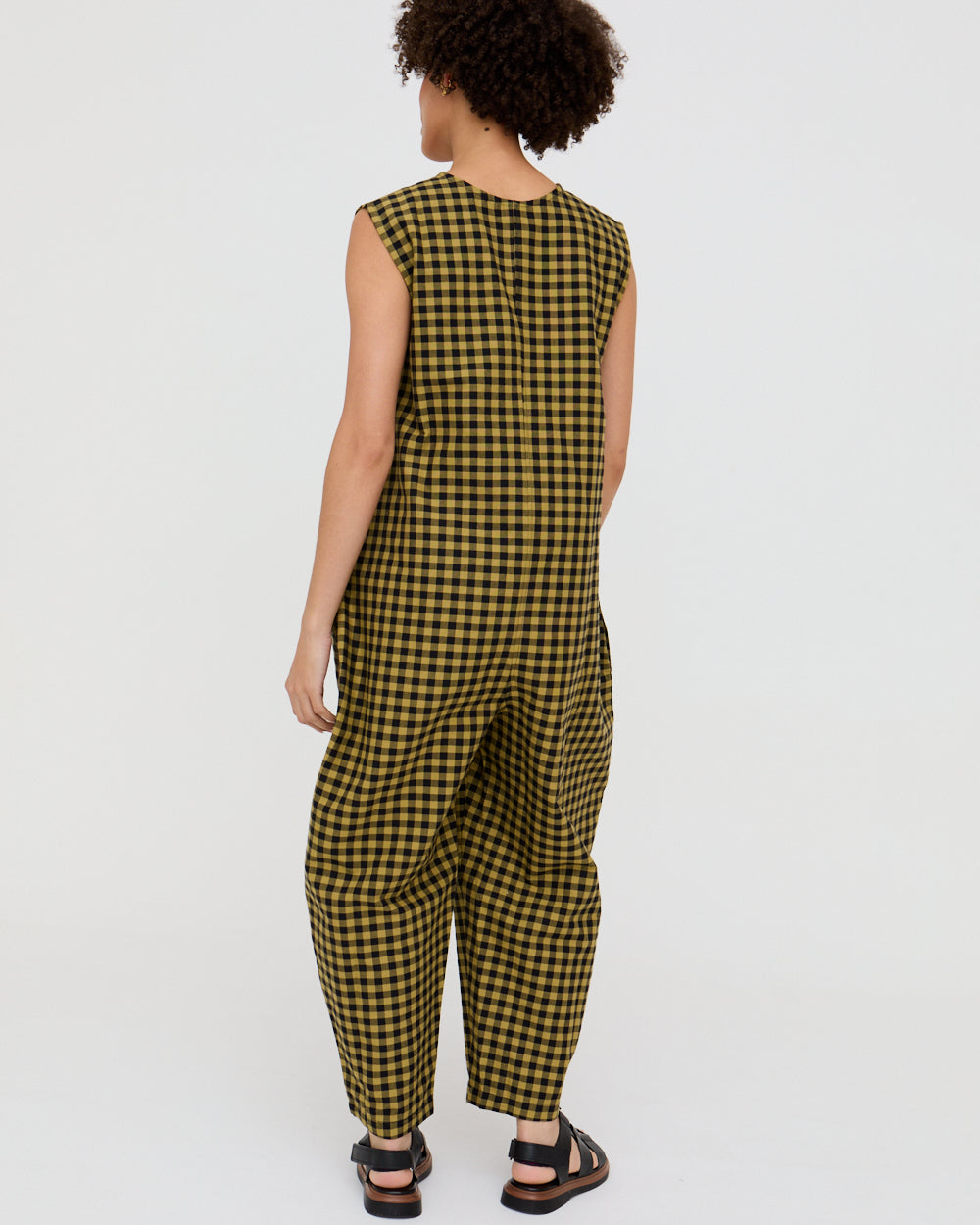 Person wearing a yellow and black checkered jumpsuit on a white background