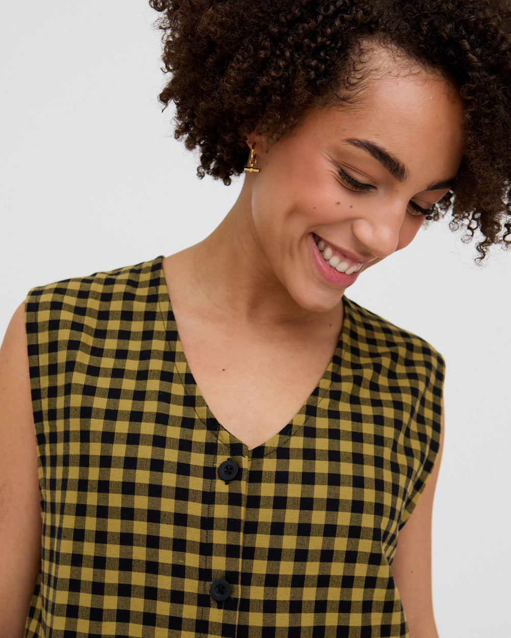 Woman wearing a yellow and black checkered dress against a white background