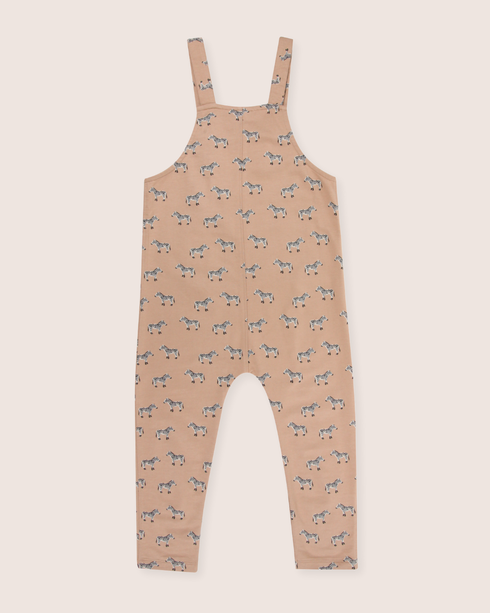 Tan zebra-patterned kids dungarees on a light pink background made from eco-friendly organic cotton, featuring shoulder straps and a loose fit for comfort and sustainability.