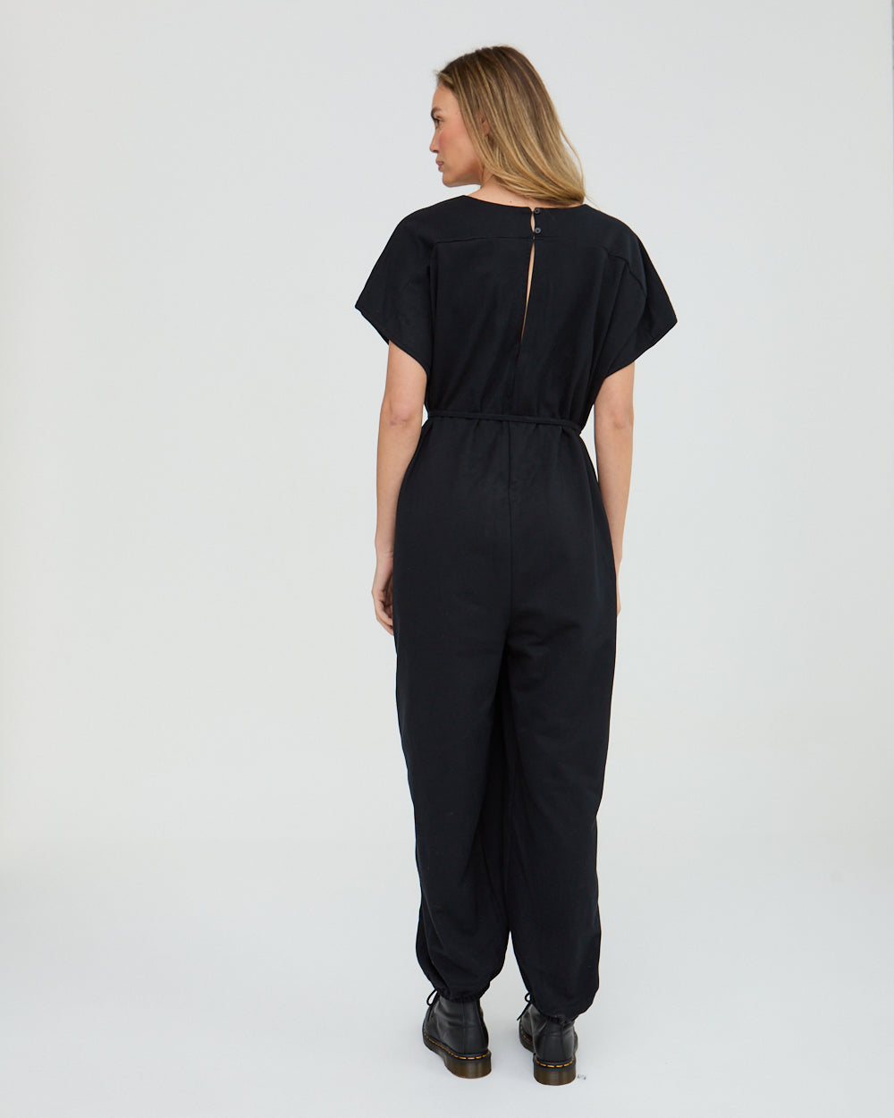 Person wearing a black jumpsuit on a white background
