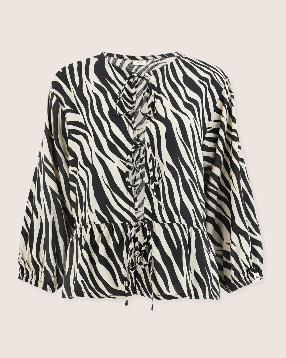 The Blake Zebra Print Tie Blouse Top is crafted from Eco Viscose with long sleeves and a round neckline. The bold black and white pattern features a ruffled front with tie details, ideal for pairing with Blake coords for a chic ensemble.