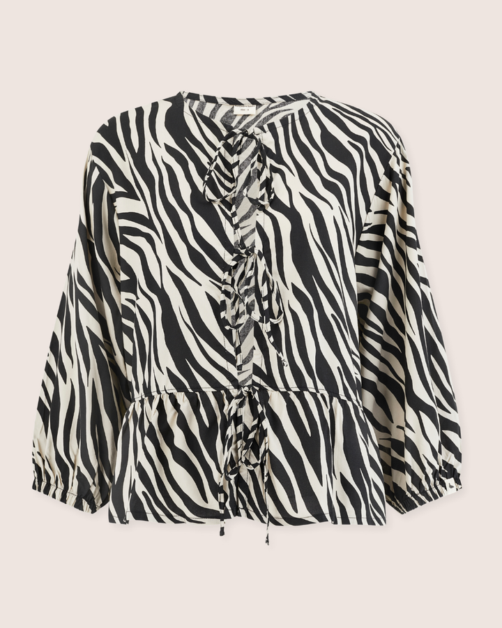 The Blake Zebra Print Tie Blouse Top is crafted from Eco Viscose with long sleeves and a round neckline. The bold black and white pattern features a ruffled front with tie details, ideal for pairing with Blake coords for a chic ensemble.