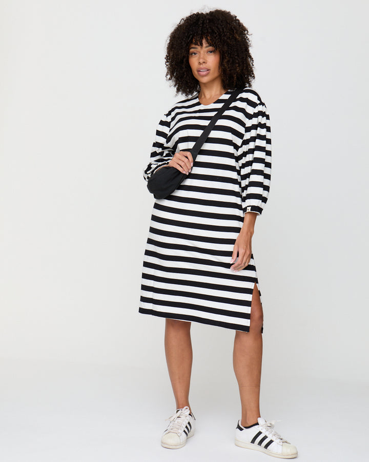 Woman wearing a black and white striped dress with a plain background