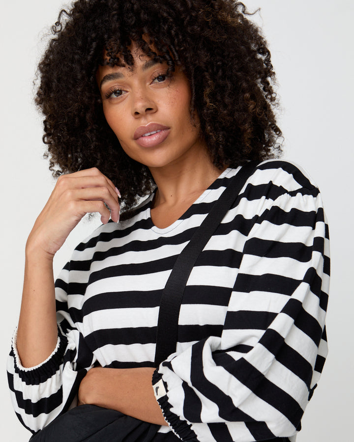 Woman wearing a black and white striped sweater against a plain background