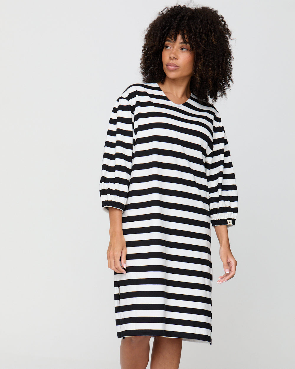 Woman wearing a black and white striped dress on a plain background