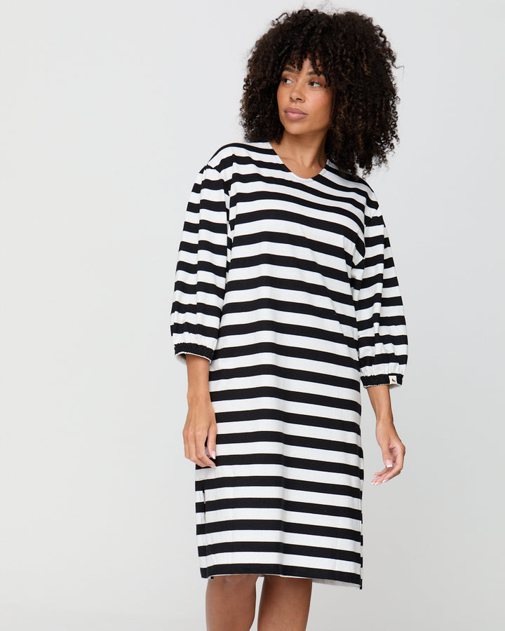 Woman wearing a black and white striped dress on a plain background