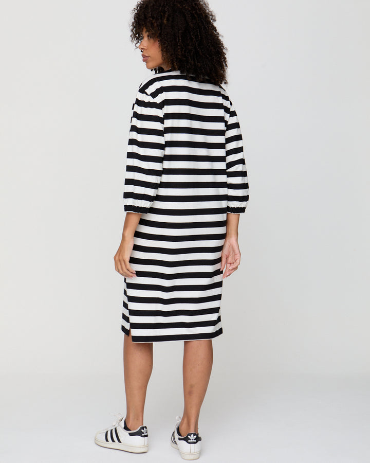 Person wearing a black and white striped dress on a plain background