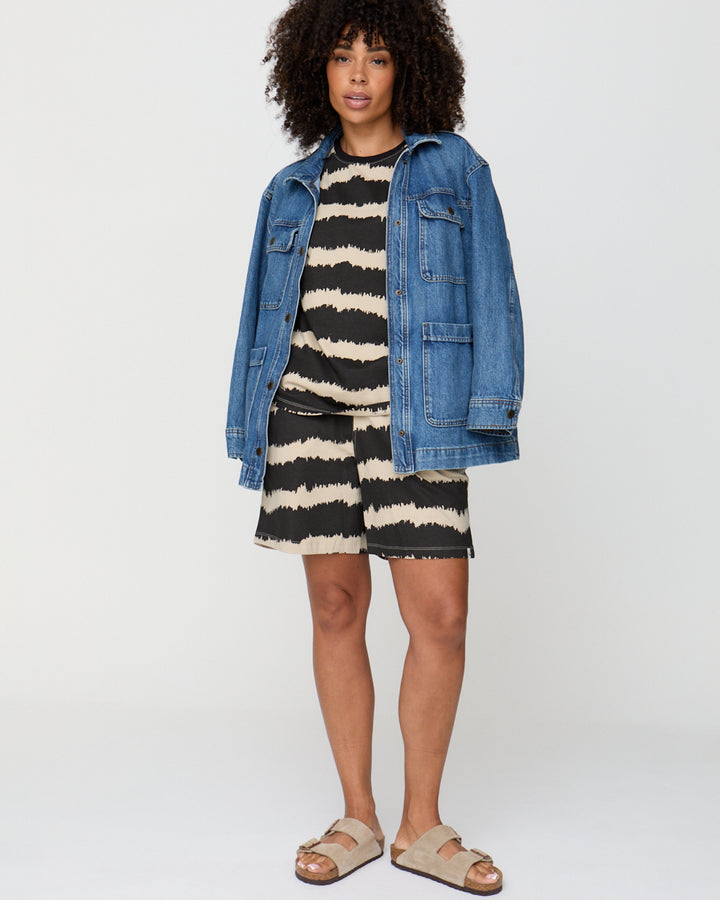 Person wearing a striped dress and denim jacket on a white background