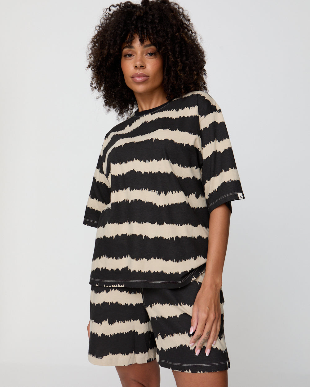 Woman wearing a black and white striped dress with a visible brand logo on a gray background