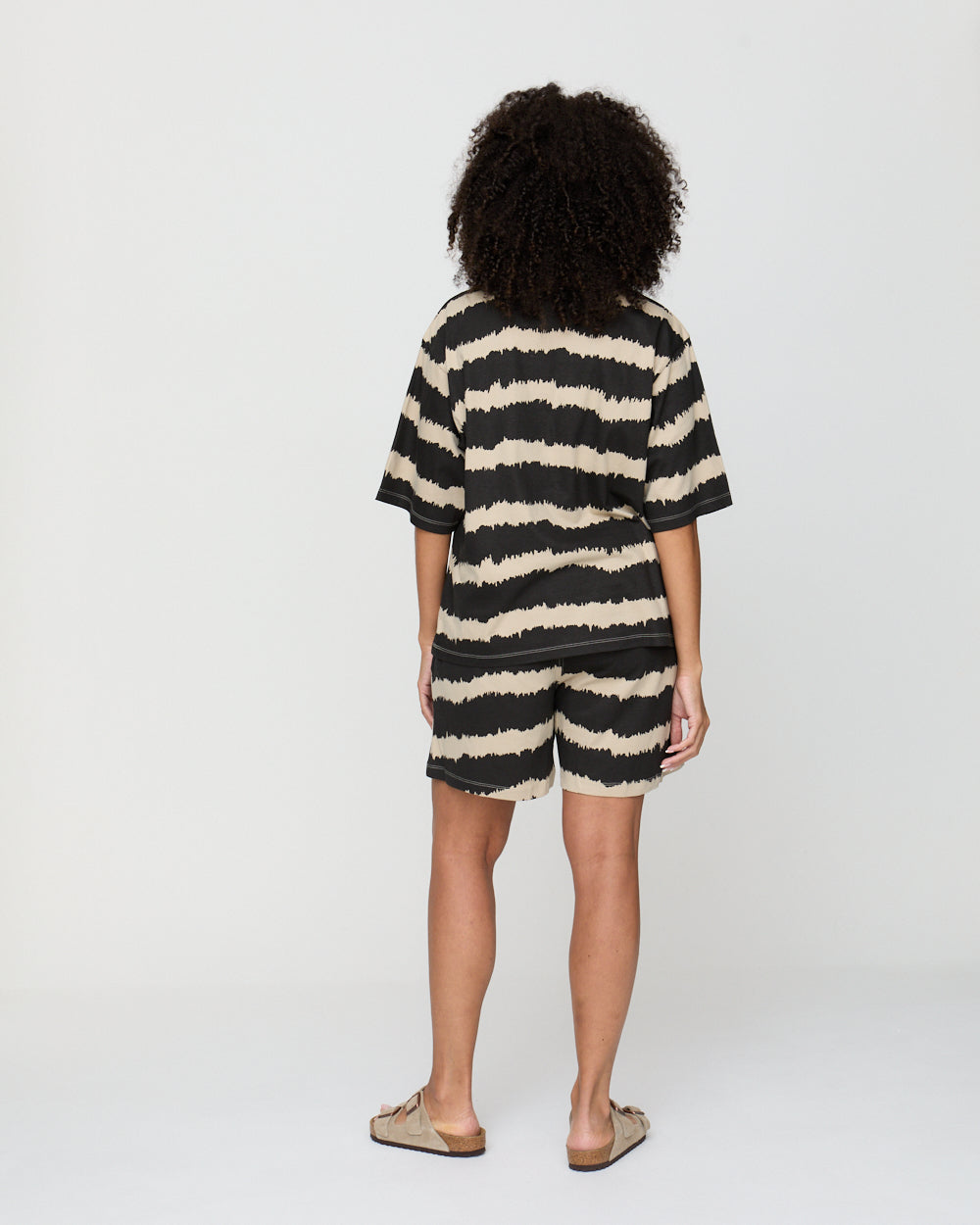 Person wearing a black and white striped outfit on a plain background