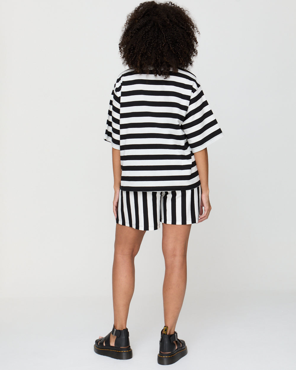 Person wearing a black and white striped dress on a plain background