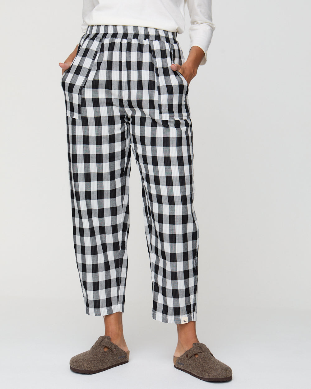 Person wearing black and white checkered pants on a white background
