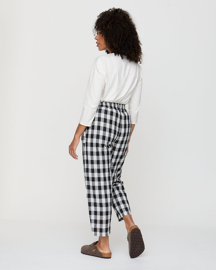 Person wearing a white shirt and black and white checkered pants on a white background