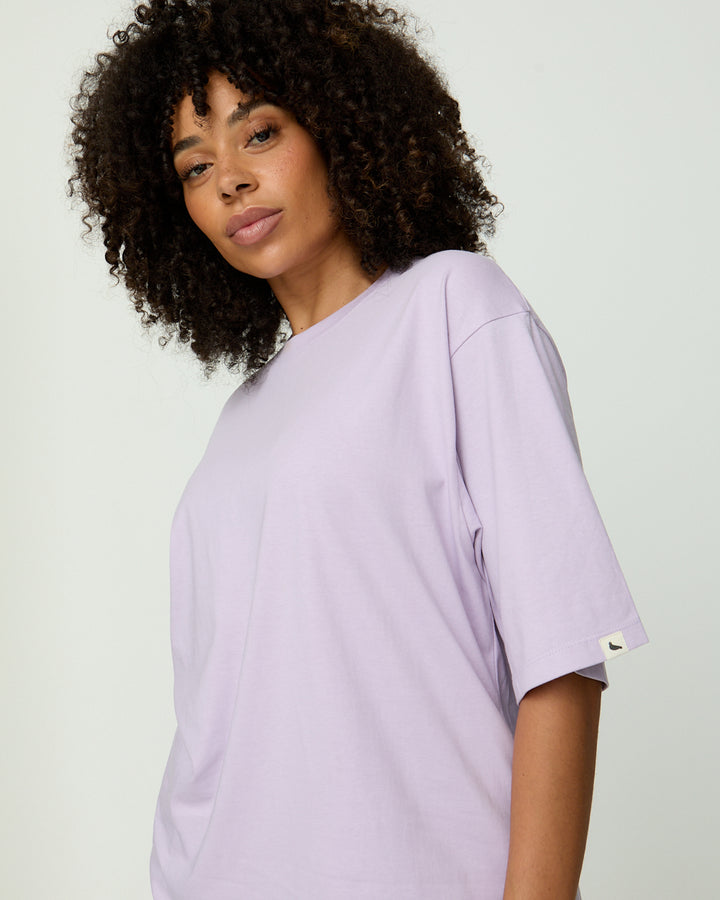 Woman wearing a light purple t-shirt against a plain background