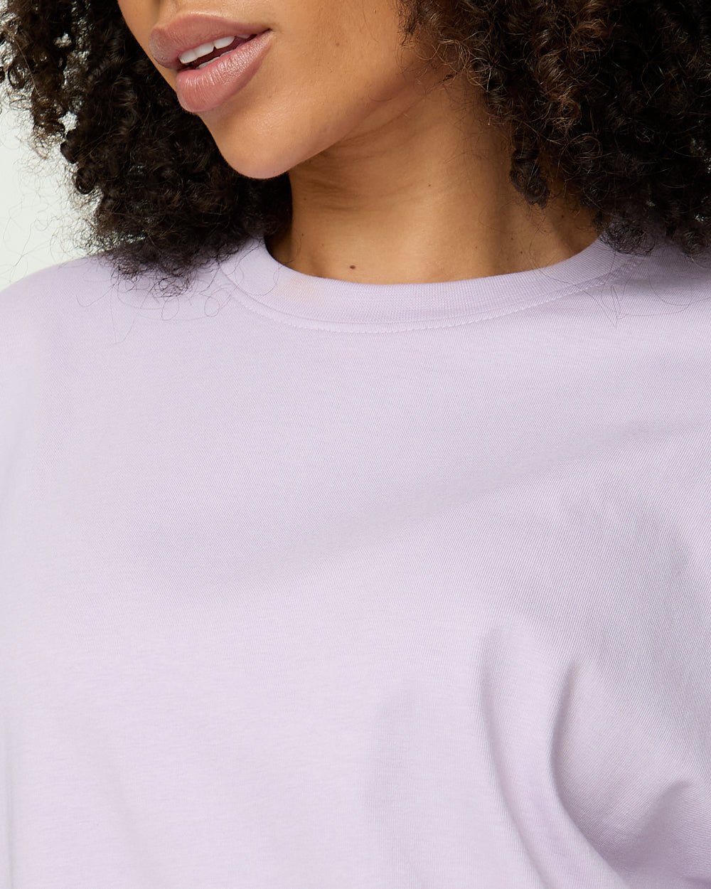 Close-up of a person wearing a light purple sweatshirt against a neutral background