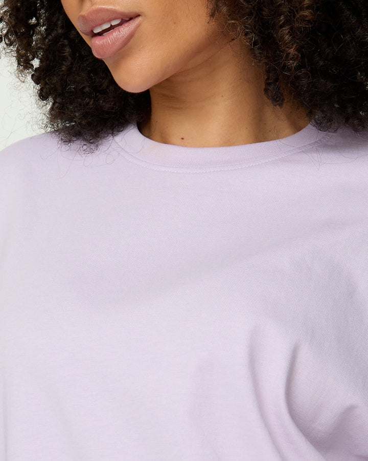 Close-up of a person wearing a light purple sweatshirt against a neutral background