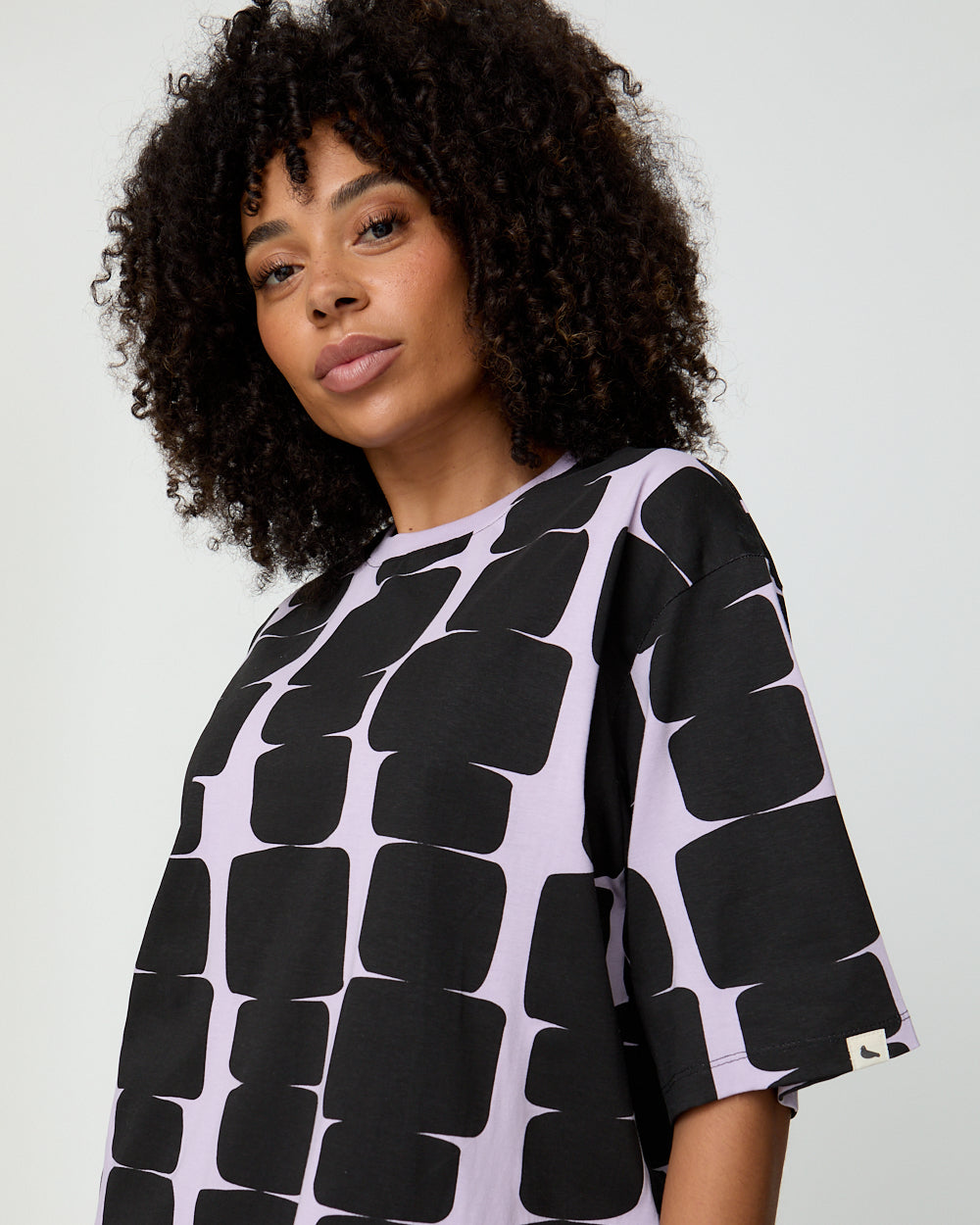 Woman wearing a black and white patterned shirt against a plain background