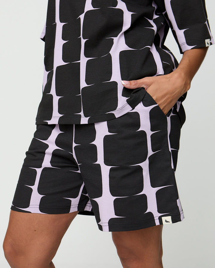 Person wearing a black and white patterned outfit on a plain background