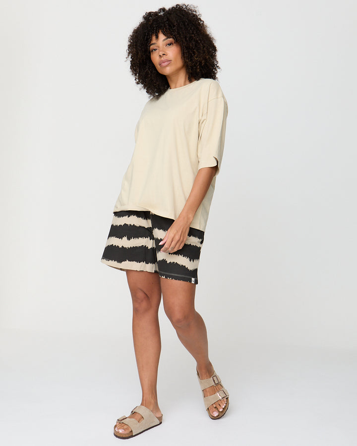 Woman wearing a beige dress with black and white striped skirt on a white background