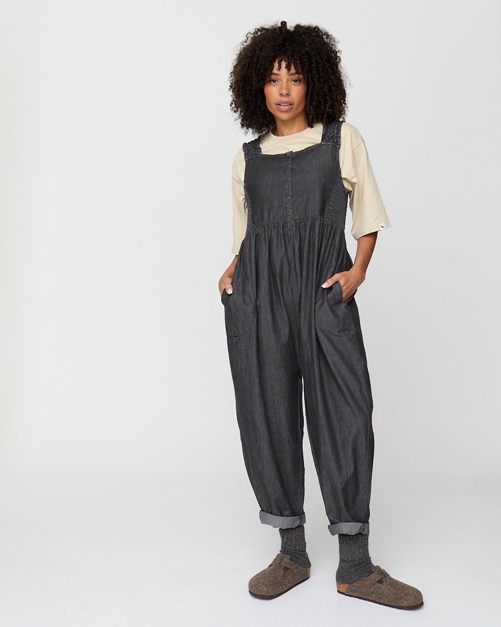 Person wearing dark gray overalls on a white background