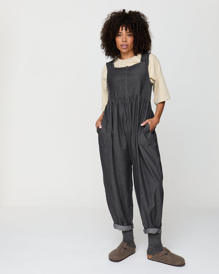 Person wearing dark gray overalls on a white background