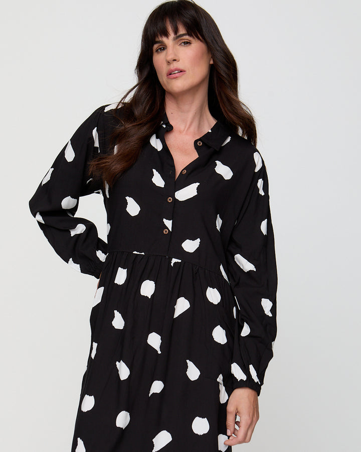 Woman wearing a black dress with white pattern against a plain background