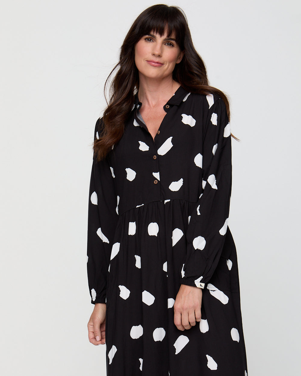 Woman wearing a black dress with white polka dot pattern on a white background