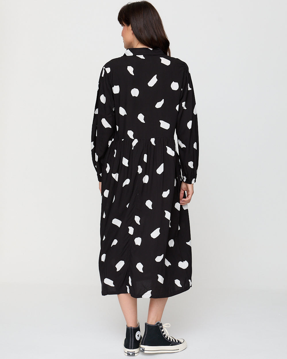 Person wearing a black dress with white pattern on a white background