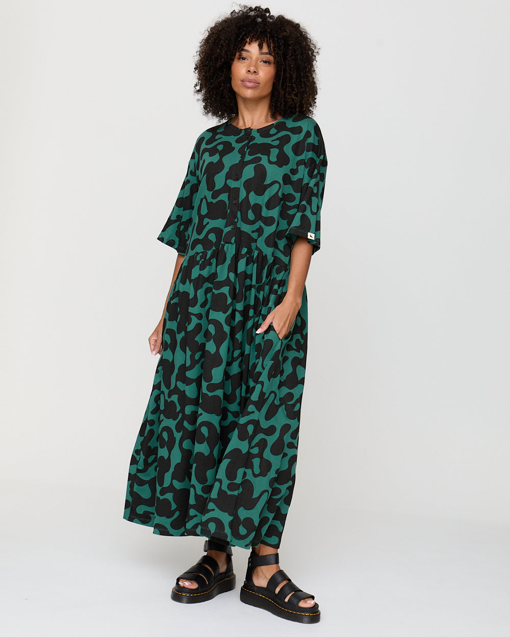 Woman wearing a green and black patterned dress on a white background