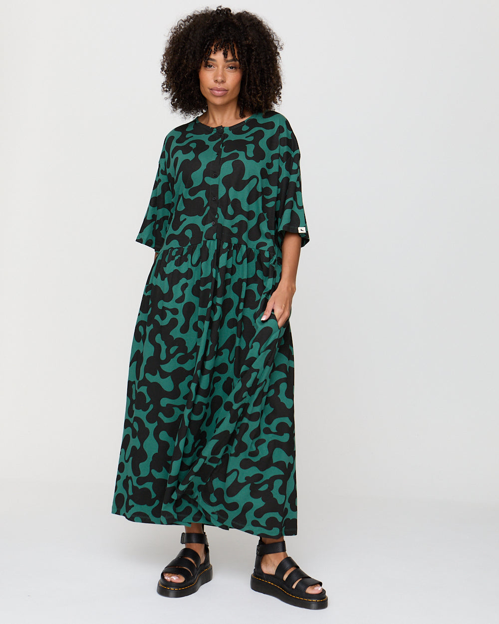 Woman wearing a green and black patterned dress on a white background