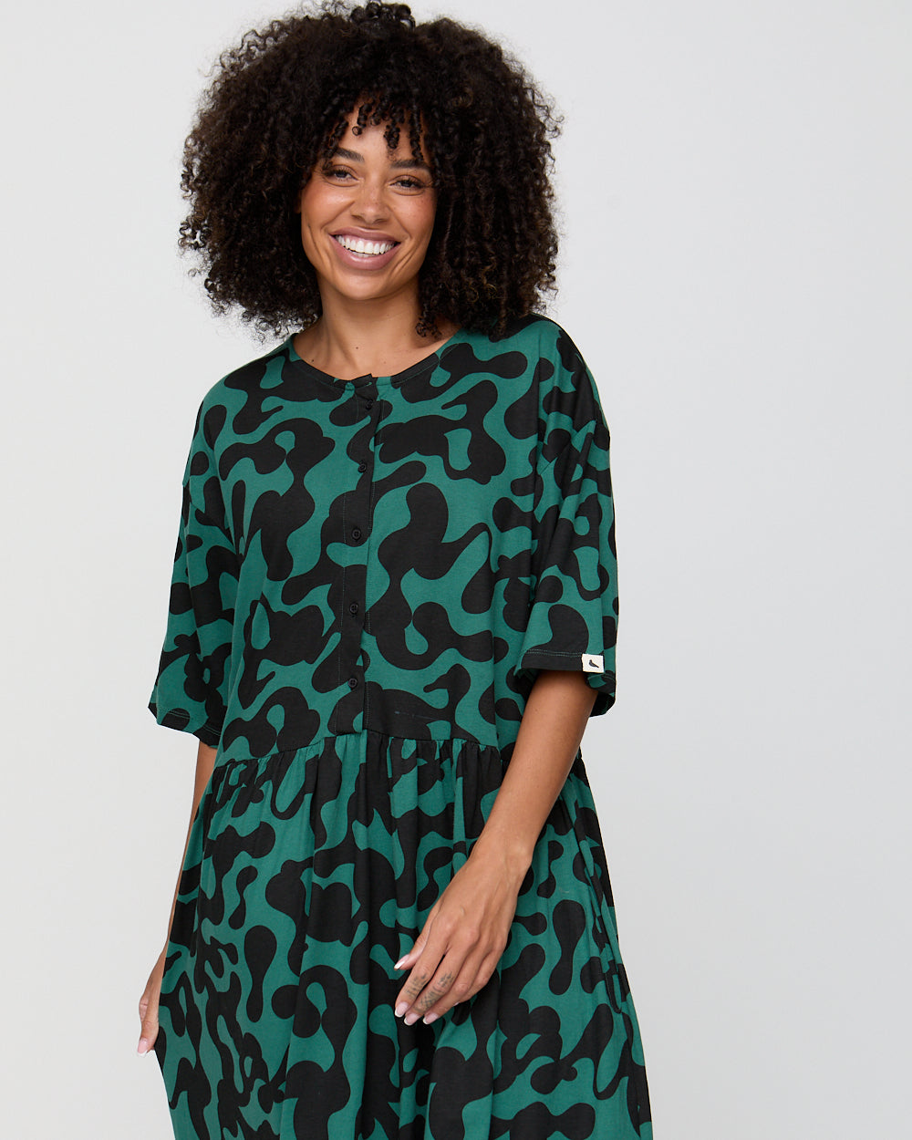 Woman wearing a green and black camouflage dress against a plain background