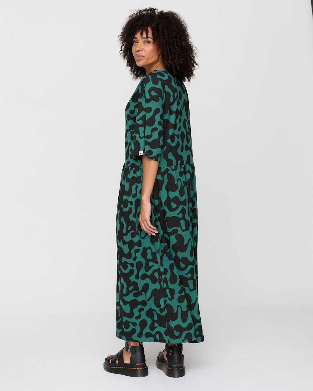 Woman wearing a green patterned dress on a white background