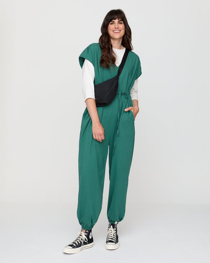 Woman wearing a green jumpsuit with a black accent on a white background