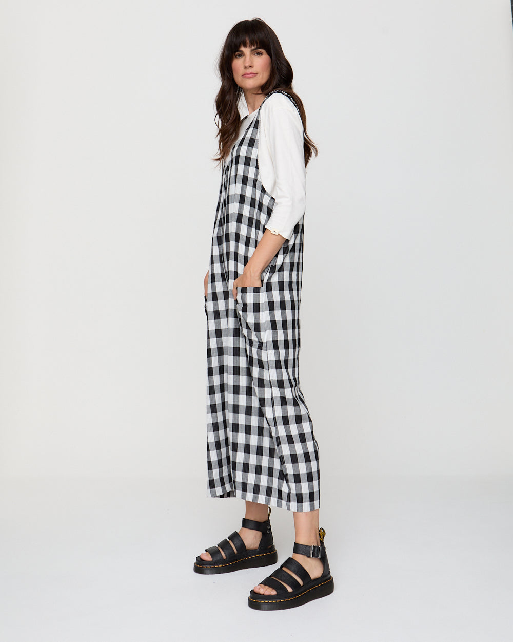 Woman wearing a black and white checkered dress with a white shirt underneath on a white background