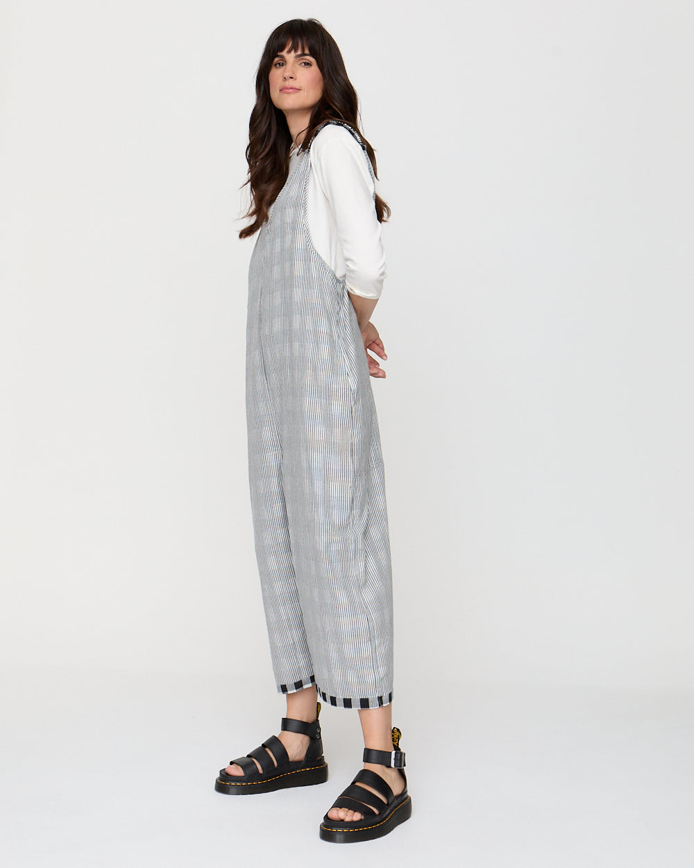 Woman wearing a gray checkered dress over a white shirt on a white background