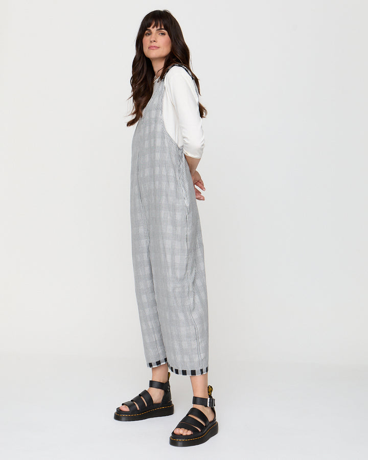 Woman wearing a gray checkered dress over a white shirt on a white background