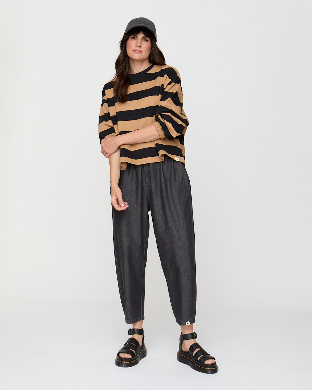 Woman wearing a striped sweater and black pants on a white background