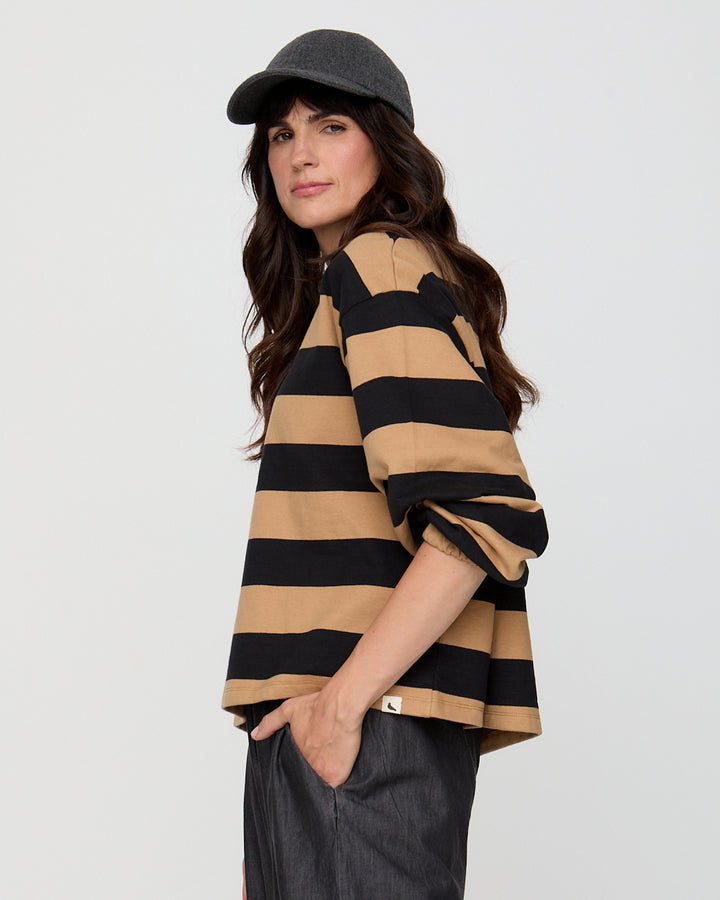 Woman wearing a black and beige striped shirt with a gray cap on a white background