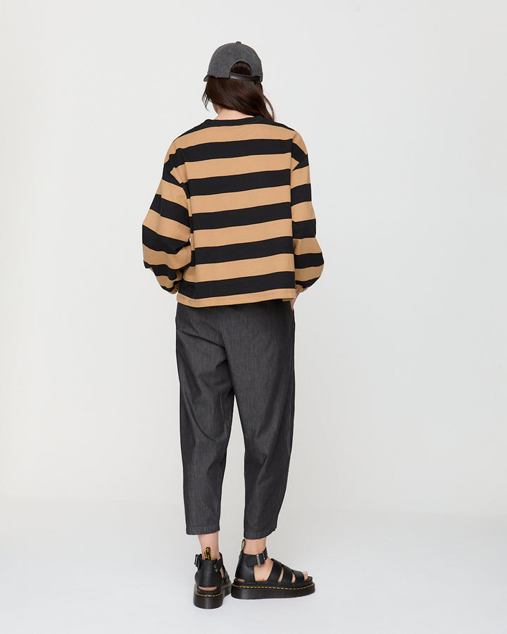 Person wearing a striped sweater and dark pants on a white background