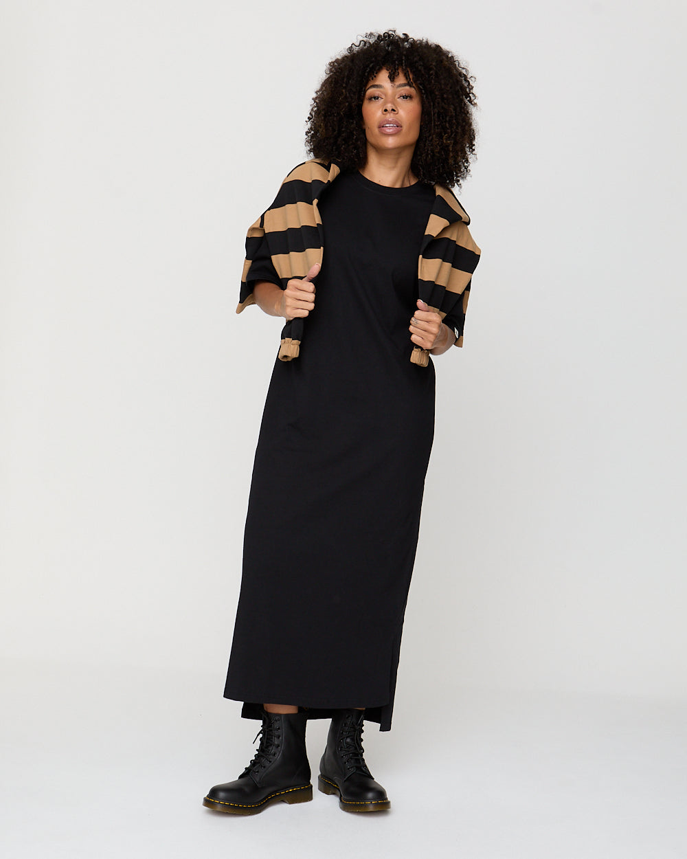 Woman wearing a black dress with a striped jacket on a white background